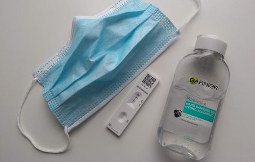 A face mask, a positive COVID-19 test, and a bottle of sanitizer.