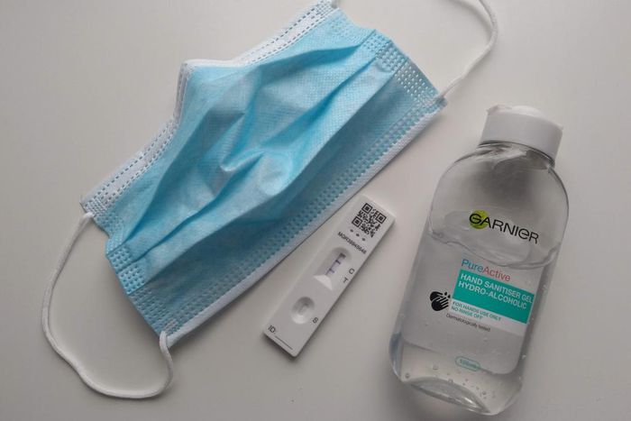 A face mask, a positive COVID-19 test, and a bottle of sanitizer.
