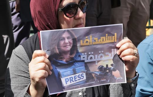 Une femme portant une affiche avec le visage de la journaliste assassinée — HAZEM BADER - AFP