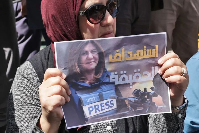Une femme portant une affiche avec le visage de la journaliste assassinée — HAZEM BADER - AFP