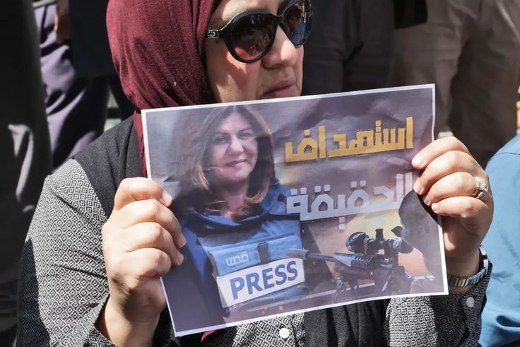 Une femme portant une affiche avec le visage de la journaliste assassinée — HAZEM BADER - AFP