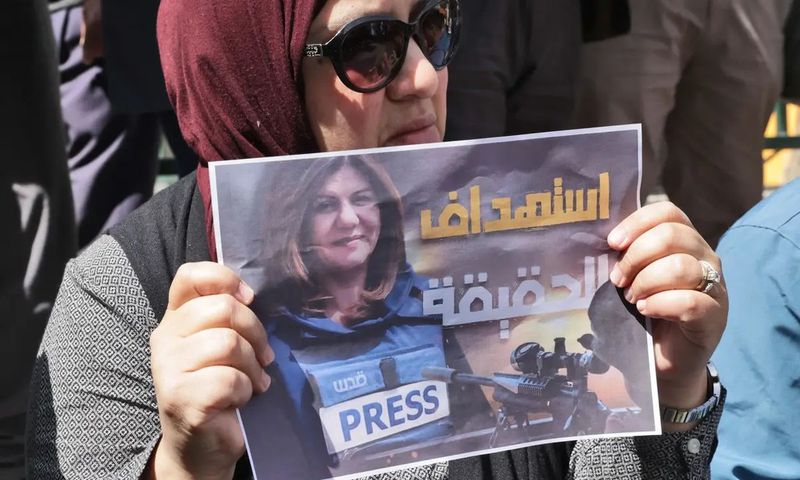 Une femme portant une affiche avec le visage de la journaliste assassinée — HAZEM BADER - AFP