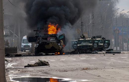 A Russian armored personnel carrier burns amid damaged and abandoned light utility vehicles after fighting in Kharkiv, Ukraine, Sunday, Feb. 27, 2022.
