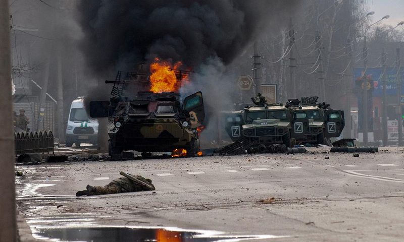 A Russian armored personnel carrier burns amid damaged and abandoned light utility vehicles after fighting in Kharkiv, Ukraine, Sunday, Feb. 27, 2022.
