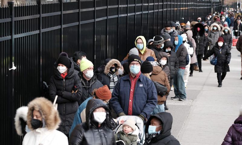 People wait in line as city workers hand out take-home COVID-19 tests in lower Manhattan on December 23, 2021.