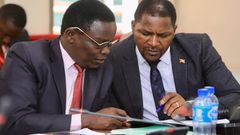 Jonathan Odur (L) peruses a document with David Zijjan, Butembe County MP