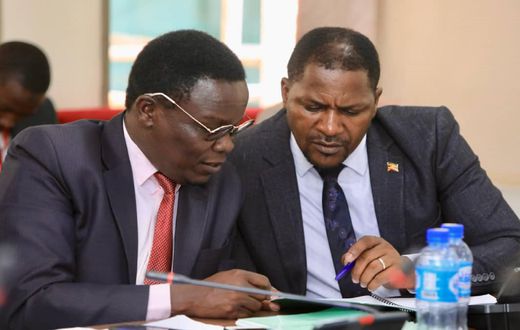 Jonathan Odur (L) peruses a document with David Zijjan, Butembe County MP