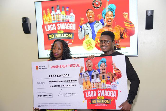 Hillary Baguma, the UBL mainstream brand manager  handing over the cash prize to the first raffle draw winner of the ongoing Laga Swagga campaign