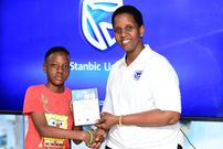 Bernice Kamahunde Mvano, Head Wealth and Investment Stanbic Bank Uganda, handing over a certificate to one of the children