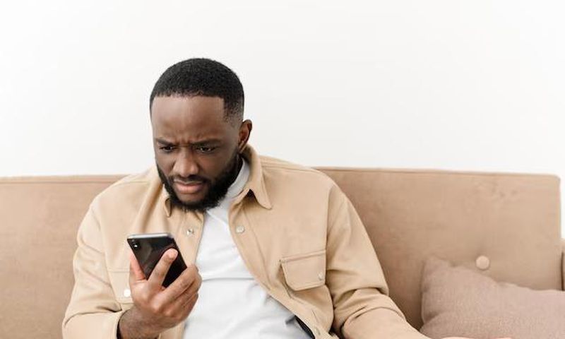 Black man angry at phone (image used for illustration) [Freepik]