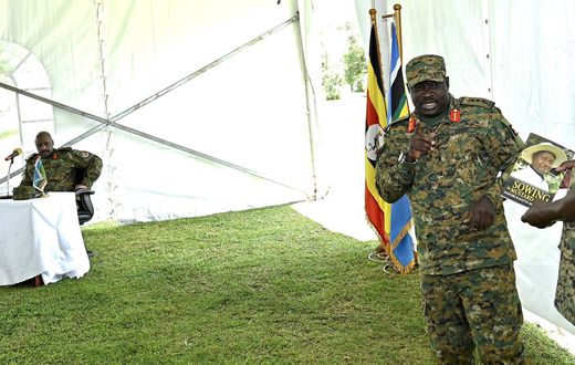 Gen Peter Elweru speaks at an event as Muhoozi Kainerugaba looks on