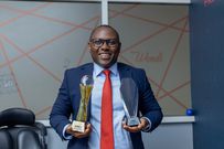 Peter Ssenyange, PostBank Uganda’s Chief Financial Officer, is posing with the awards