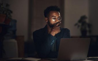 Shot of a young businessman using a laptop during a late night at work