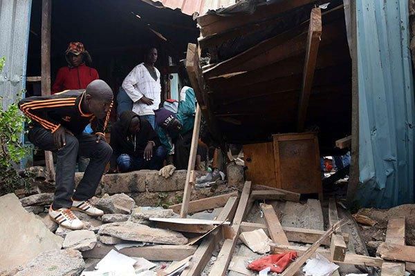 People looking inside a collapsed classroom at Precious Talent Academy