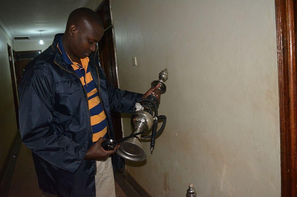 A police officer holding  a confiscated Shisha tube during one of the raids in Kampala in 2016