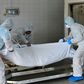Employees lift the body of a COVID-19 victim before loading it into the furnace at the New Sonapur Hindu crematorium in Dubai