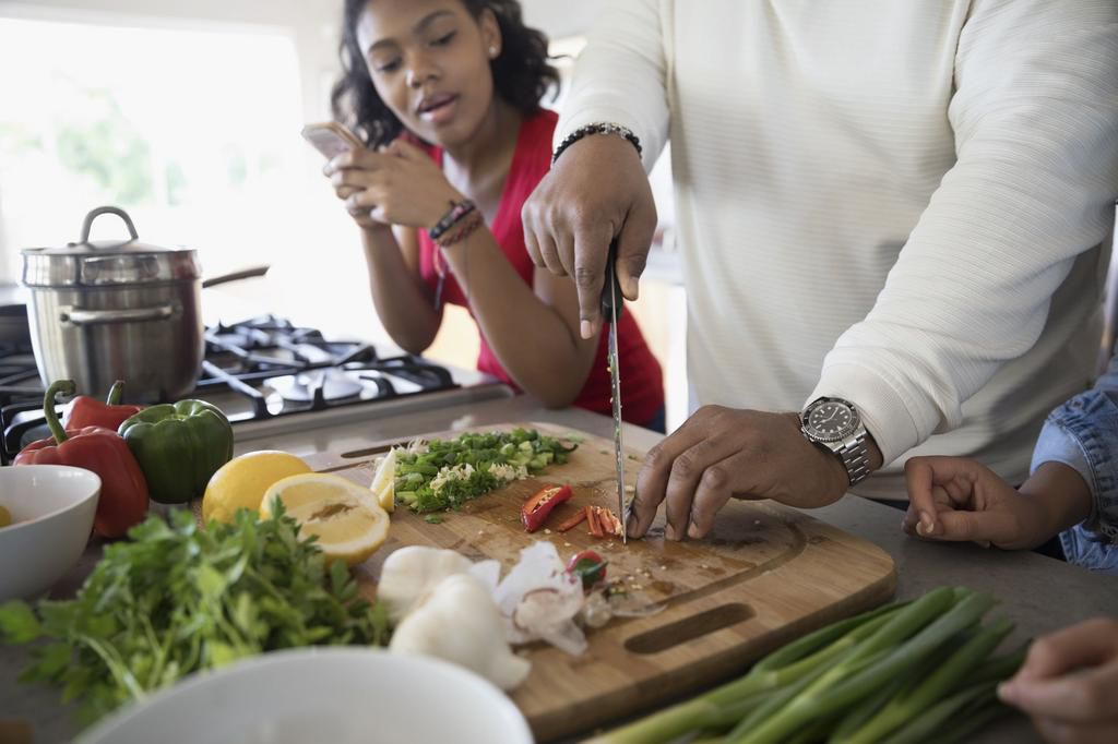 African American father and daughter cooking in kitchen