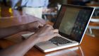 Black African man sitting at a restaurant typing on his laptop computer.