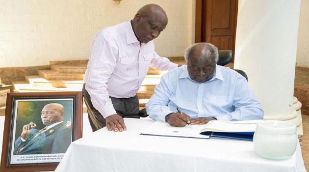 Retired President Mwai Kibaki signing a condolence book for Mzee Daniel arap Moi