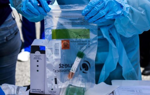 A health worker stores coronavirus test samples at a drive-through clinic in West Palm Beach, Florida