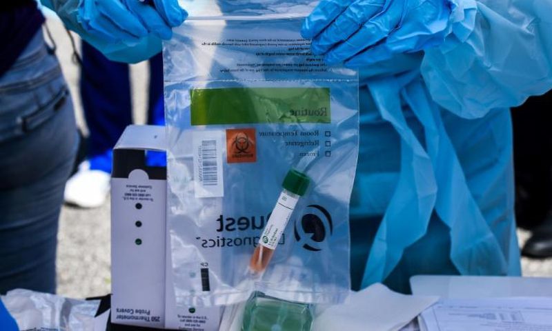 A health worker stores coronavirus test samples at a drive-through clinic in West Palm Beach, Florida