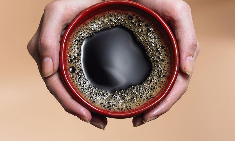 &quot;Woman holding coffee cup, close-up, overhead view&quot;