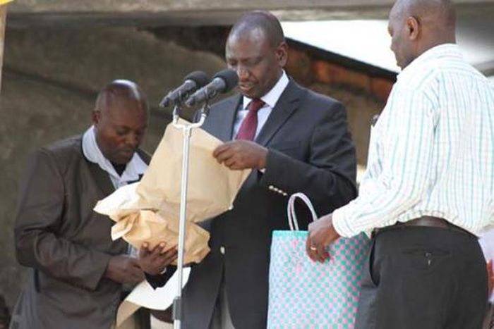 File image of DP Ruto holding cash donations at a past harambee
