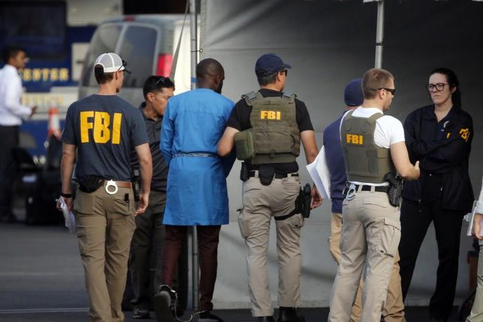 FBI agents holding one of the suspect arrested in the crack down on internet fraud