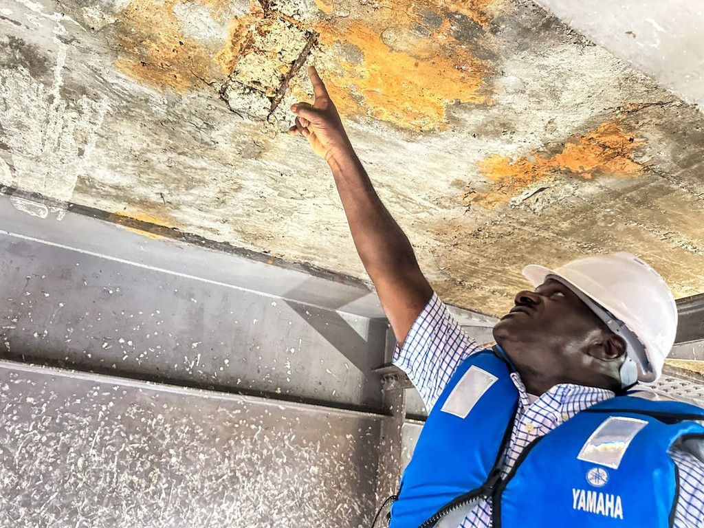 Minister Katumba points to a rusted patch underneath Karuma Bridge