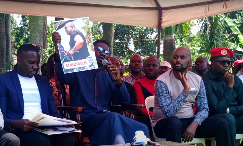 Bobi WIne displays a photo of one of the police officers involved in the Tuesday incident