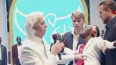 Pastor Benny Hinn prays for a woman at the crusade