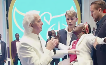Pastor Benny Hinn prays for a woman at the crusade
