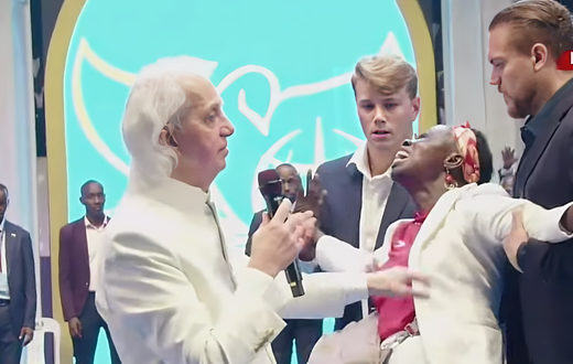 Pastor Benny Hinn prays for a woman at the crusade