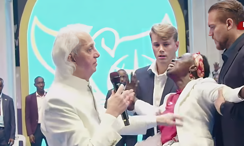 Pastor Benny Hinn prays for a woman at the crusade
