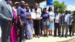Minister Fiona Nyamutoro hands over a land title to one of the PAPs in Buliisa