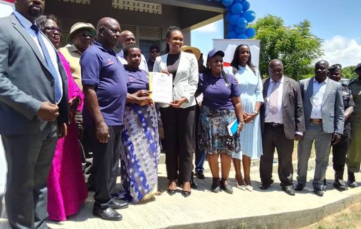 Minister Fiona Nyamutoro hands over a land title to one of the PAPs in Buliisa