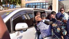 Akamba being bundled into a van by security