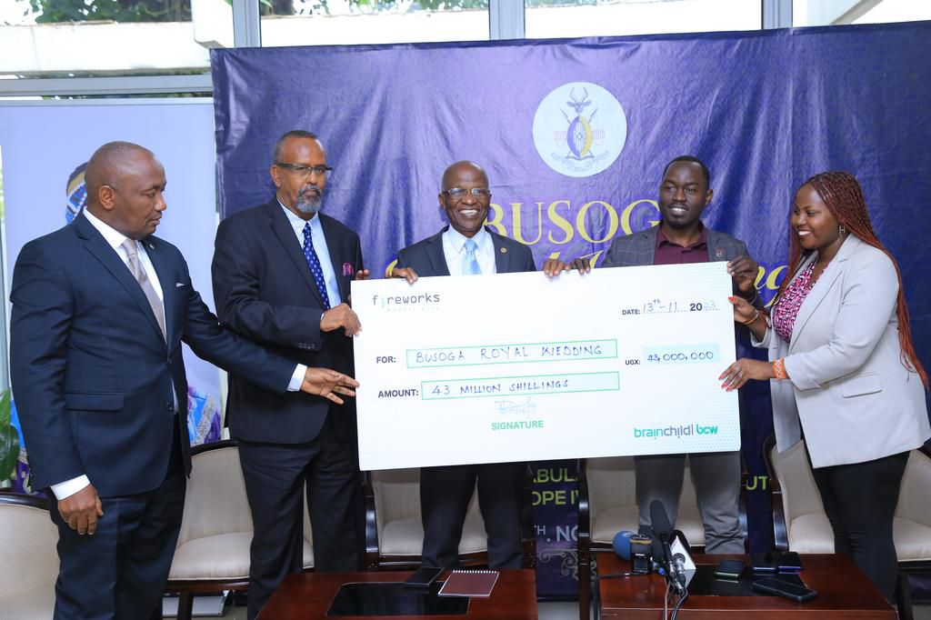 Walter Wafula, the General Manager of Brain Child PCW, handing over a dummy cheque to Patrick Batumbya, the chairman of Royal Wedding Organizing Committee
