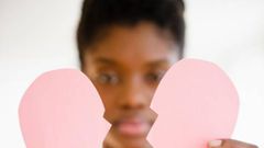 Woman holding a broken paper heart