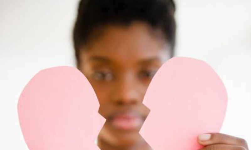 Woman holding a broken paper heart