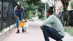 Mum and dad walking with their daughter outside [Image Credit: Greta Hoffman]