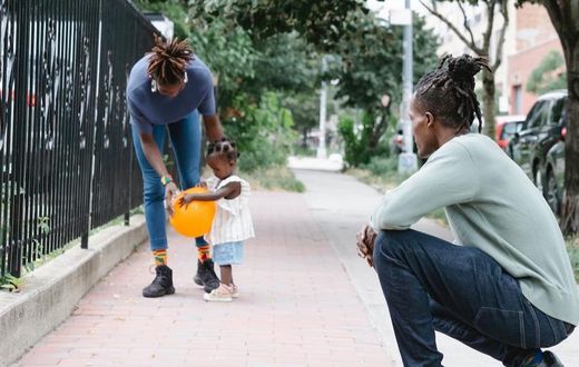Mum and dad walking with their daughter outside [Image Credit: Greta Hoffman]