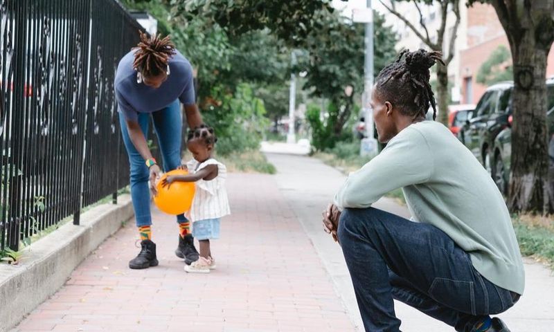Mum and dad walking with their daughter outside [Image Credit: Greta Hoffman]