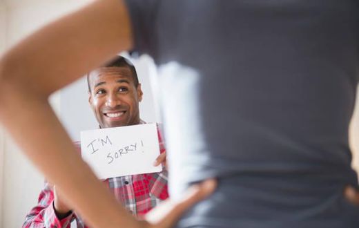Man showing 'I'm Sorry' sign to angry girlfriend