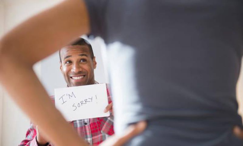 Man showing 'I'm Sorry' sign to angry girlfriend