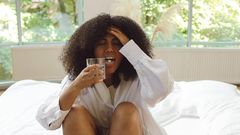 Woman in white long-sleeve shirt sitting on a bed [Image Credit: Polina Tankilevitch]