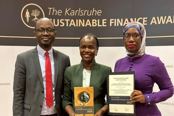 UDB Managing Director, Patricia Ojangole (C), holding the accolade she won for the Sustainability Leader of the Year 2023 at the prestigious Annual Karlsruhe Sustainable Finance Awards in Germany together with UDB Chief Internal Auditor, Stephen Hamya ...