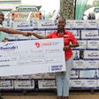 Amos Wekesa receives the dummy check from  Pearl Nimusiima, CCBU Public Affairs, and Communications Manager