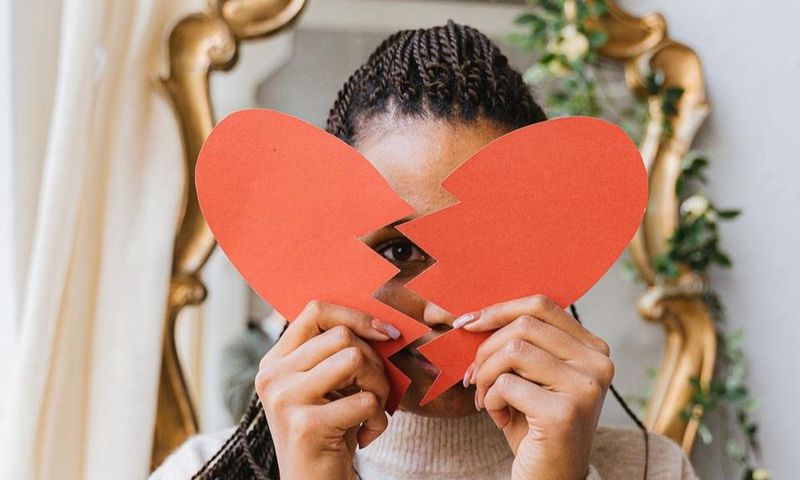 A woman holding a broken heart made of paper [Image: Antoni Shkraba]