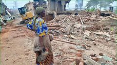 A woman stands over what was left of her house after the NEMA operation